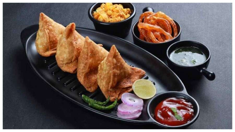 चाय और हरी चटनी के साथ परोसे गए क्रिस्पी और गोल्डन ब्राउन समोसे।